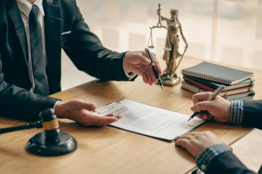 İş adamı ve avukat hukuki konuları tartışıyor ve hukuk bürosundaki bir takım toplantısında hakimin çekiciyle anlaşma imzalıyor..