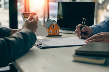 Bir emlakçı ya da satış müdürü satış sunar ve ev satın alma sözleşmesi ve ücretsiz sigorta şartlarını açıklar. İpotek konsepti ve emlak satış sonrası servisi