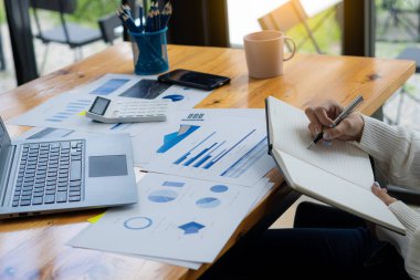 Yakın plan fotoğraf. Elinde kalem tutan ve finansal belgelere finansal pazarlama ağı şeması olan ve dizüstü bilgisayar üzerinde çalışan bir iş adamı. çevrimiçi muhasebe kavramı