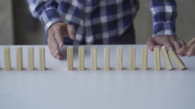 Bir iş adamının eli, ofisteki masaya düşen tahta bloğu durdurur. İş Konseptinde domino etkisi Risk Yönetimi 4k Yavaş Hareket