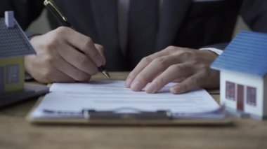 Emlakçı yatırım raporu fikri: İşadamı, iki yan evle birlikte masanın üzerinde emlak projesinin ipotek grafiği belgesini kontrol edip imzaladı