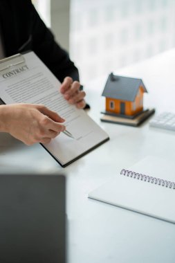 Emlak komisyoncuları, ev satış temsilcileri, müşterilere verilecek ev sermaye kredisi belgeleri ve ev tapusu sözleşmeleri üzerinde çalışmalar. Ofisteki masada.