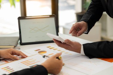 İki işadamı mali bütçe veya maliyet şirketlerinin grafik raporlarını ve analizini tartıştı. Ofisteki hesap makinesini kullanarak bir iş stratejisi üzerinde fikir alışverişinde bulunmak için iş arkadaşlarıyla buluşacağım..