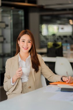 Bilgisayarda çalışan Asyalı iş kadını, mali istatistik veri analizi grafiklerine bakan masa başında çalışan bir kadınla birlikte iş dünyasının dikey imajı üzerinde çalışıyor.