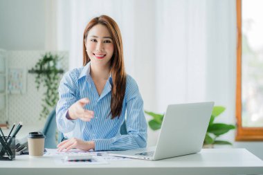 Asyalı iş kadını elini kameraya uzatıp mali muhasebe konsepti masasında el sıkışıyor.