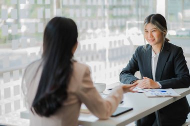 Asya Muhasebeciler ve İş Kadınları Konferansı Modern bir ofiste finansal verileri tartışan ve analiz eden iki kişi verileri, grafikleri, finans ve gelirleri analiz eder. piyasa karı