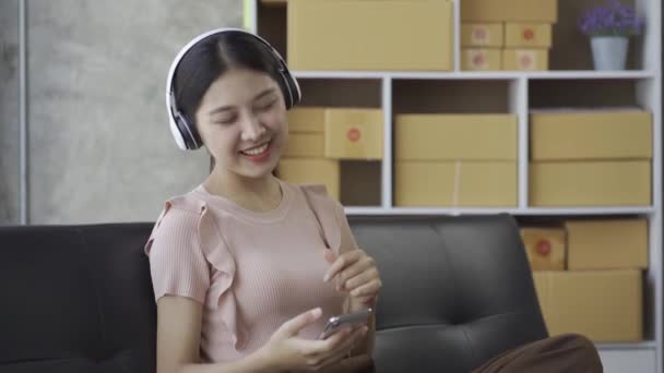 Kulaklık Takan Genç Bir Asyalı Kadın Evdeki Kanepede Seve Seve — Stok video