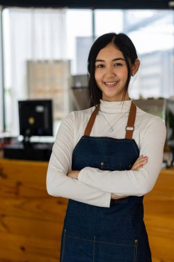 Önlüklü Asyalı kadın kafe yiyecek ve içecek konseptinin önünde duruyor.