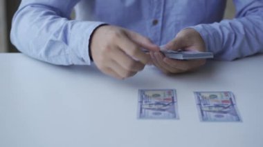 Yakın plan Asyalı eli para sayıyor Meçhul genç adam ev finans ve zenginlik konseptlerindeki bir evde nakit dolar hesaplıyor