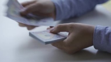 Yakın plan Asyalı eli para sayıyor Meçhul genç adam ev finans ve zenginlik konseptlerindeki bir evde nakit dolar hesaplıyor