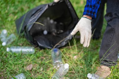 Genç bir adam plastik şişeleri ve siyah poşetleri topluyor ve onları geri dönüşüm için toplayanlara satmak üzere biraraya getiriyor. Atık ayırma ve çevre koruma kavramı