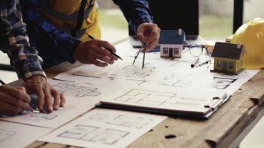 İnşaat mühendisliği ekibi, mimar ve ustabaşı ile birlikte planları izliyorlar. Ev yapımı ve inşaat planlama 4K video için ev tasarımlarını kontrol ediyorlar..