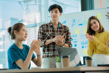 Gelişigüzel giyinen bir grup yaratıcı Asyalı ofis projelerinin başarısını kutlamak için el ele tutuşuyor. Başlangıçta birçok erkek ve kadın birlikte durdu. Meslektaşların takım çalışması kavramı