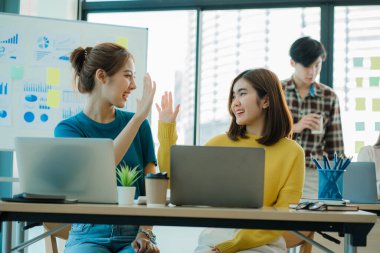 Gelişigüzel giyinen bir grup yaratıcı Asyalı ofis projelerinin başarısını kutlamak için el ele tutuşuyor. Başlangıçta birçok erkek ve kadın birlikte durdu. Meslektaşların takım çalışması kavramı