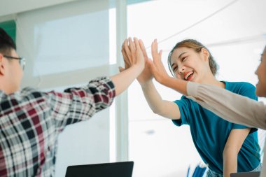 Gelişigüzel giyinen bir grup yaratıcı Asyalı ofis projelerinin başarısını kutlamak için el ele tutuşuyor. Başlangıçta birçok erkek ve kadın birlikte durdu. Meslektaşların takım çalışması kavramı