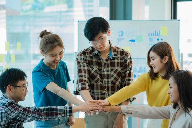 Gelişigüzel giyinen bir grup yaratıcı Asyalı ofis projelerinin başarısını kutlamak için el ele tutuşuyor. Başlangıçta birçok erkek ve kadın birlikte durdu. Meslektaşların takım çalışması kavramı