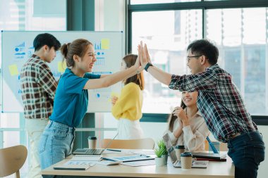 Gelişigüzel giyinen bir grup yaratıcı Asyalı ofis projelerinin başarısını kutlamak için el ele tutuşuyor. Başlangıçta birçok erkek ve kadın birlikte durdu. Meslektaşların takım çalışması kavramı
