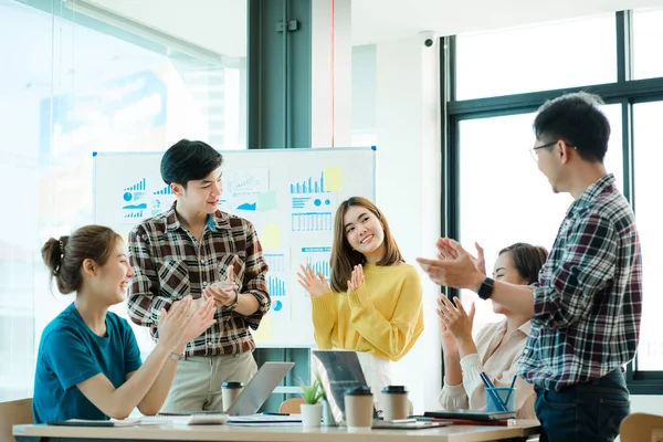 Gelişigüzel giyinen bir grup yaratıcı Asyalı ofis projelerinin başarısını kutlamak için el ele tutuşuyor. Başlangıçta birçok erkek ve kadın birlikte durdu. Meslektaşların takım çalışması kavramı