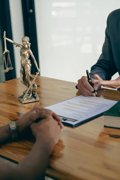 Business people or lawyers discussing contracts or business deals at a law firm. Justice advice service concept with hammer and goddess of justice beside, vertical image.