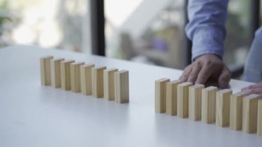 4K ağır çekim. İş adamının elleri düşmeyi durdurur. İş krizi. Risk yönetimi ya da domino konseptini önlemek. Risklerin etkisi iş krizi ahşap masa üzerinde