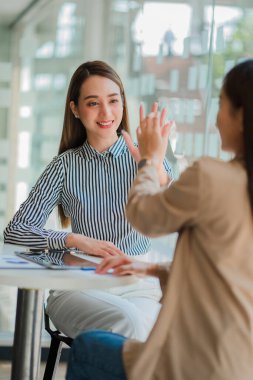 İki Asyalı iş kadını bir toplantıda fikirlerini tartıştı. İki kişi yatırım projeleri ve planlama stratejileri hakkında tartıştı. İşadamı ofiste dizüstü bilgisayarla konuşuyor.