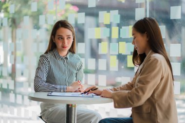 İki Asyalı iş kadını bir toplantıda fikirlerini tartıştı. İki kişi yatırım projeleri ve planlama stratejileri hakkında tartıştı. İşadamı ofiste dizüstü bilgisayarla konuşuyor.