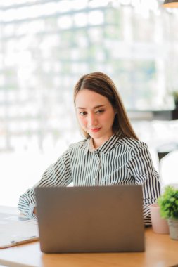 Laptop bilgisayarında hesap makinesiyle çalışan genç Asyalı iş kadını çizelgeleri, iş planlarını, yatırımları, finansal veya muhasebe kavramlarını analiz etmeyi planlıyor. dikey resim