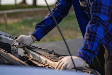 Teftiş aracının önünde duran Asyalı adam evdeki araba motorundaki makine sorunlarını inceliyor ve arabanın içinde tamir edilecek sorunlar buldu. Asyalı bir adamın araba motoru var.