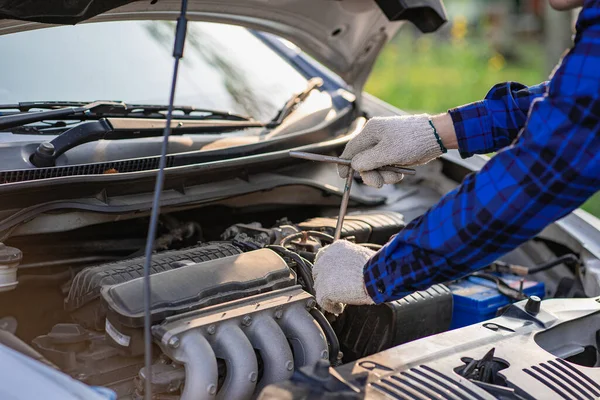 Asian man standing in front of inspection vehicle and inspecting machinery Problems in the car engine in the house and found problems inside the car to repair. Asian man maintains a car\'s engine