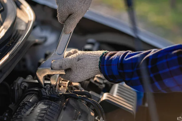 Asian man standing in front of inspection vehicle and inspecting machinery Problems in the car engine in the house and found problems inside the car to repair. Asian man maintains a car\'s engine