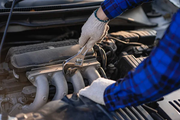 Asian man standing in front of inspection vehicle and inspecting machinery Problems in the car engine in the house and found problems inside the car to repair. Asian man maintains a car\'s engine