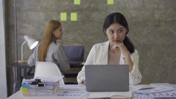 两名年轻的亚洲女商人从事财务文件工作 分析投资项目和规划战略方面的信息 与在办公室在线工作的笔记本电脑交谈的商人 — 图库视频影像
