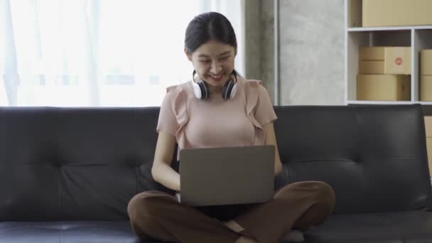 Boynuna Kulaklık Takan Asyalı Bir Kadın Evdeki Internet Çalışmasında Konseptinde — Stok video