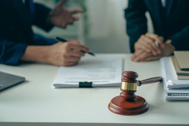 Erkek avukatlar ya da hakimler, müşteriler, iş ve hukuki hizmetler için ekiplere danışırlar. Danışman, adalet ve avukat kavramının önüne konan çekiçle imzalanan sözleşmeyi sunar.