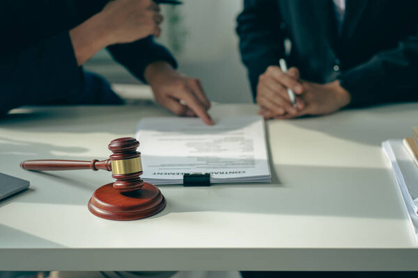 Male attorneys or judges consult teams with clients, business and legal services. The consultant presents the contract signed with the hammer placed in front and concept of justice and lawyer