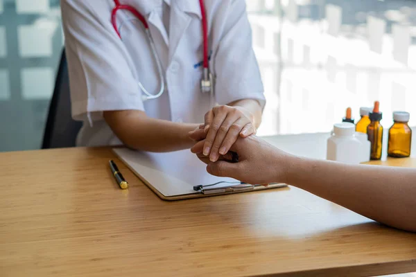 Close-up of a female doctor holding a patient\'s hand giving encouragement and advice at Medicare Clinic Hospital Doctor talking to patient, giving hope, mental health, therapy, comfort at the table.