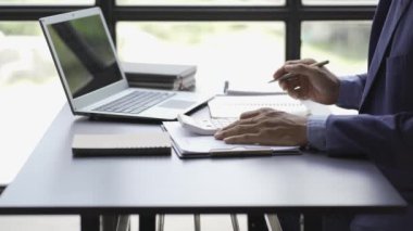 Muhasebecinin elleri mali raporlar oluşturmak için mali belgeler, hesap makineleri ve dizüstü bilgisayarlar üzerinde çalışıyor. Pazarlama grafikleri istatistik analiziyle çalışan bir işadamı