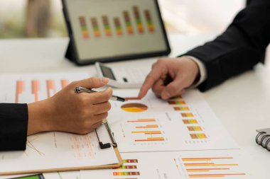 İki iş ortağı bütçe toplantıları sırasında mali ve şirket planlama grafiklerini tartışıyor ve iş adamı ofisteki dizüstü bilgisayarda yatırım pazarlama analizi planlıyor..