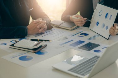 İki iş ortağı bütçe toplantıları sırasında mali ve şirket planlama grafiklerini tartışıyor ve iş adamı ofisteki dizüstü bilgisayarda yatırım pazarlama analizi planlıyor..