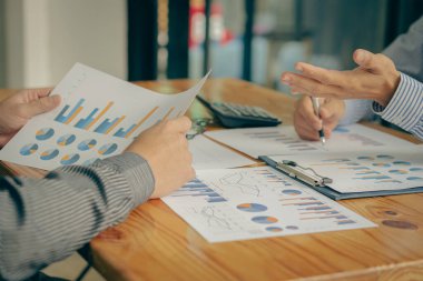 İki iş ortağı bütçe toplantıları sırasında mali ve şirket planlama grafiklerini tartışıyor ve iş adamı ofisteki dizüstü bilgisayarda yatırım pazarlama analizi planlıyor..