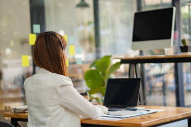 Başarılı Asyalı iş kadını masasında oturmuş kulaklık takıyor ve bir müşteri toplantısıyla bilgisayarla konuşuyor. finansal muhasebe kavramı