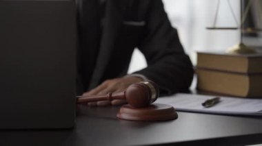 Hukuk bürosu avukatı çekiçle çalışıyor ve sözleşme belgeleriyle birlikte dizüstü bilgisayarla online danışman 4k video üzerinde çalışıyor.