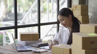 Bir KOBİ başlatın, kutulu laptop kullanan bağımsız Asyalı kadınlardan oluşan küçük bir girişimci. neşeli başarı Online pazarlama paketleme kutuları üzerinde çalışan kadın ve KOBİ konseptleri 4k video teslim