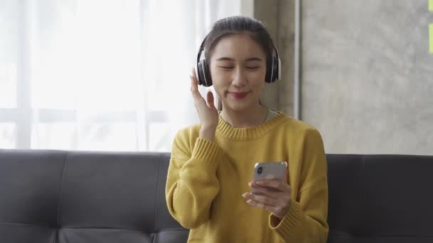 Asyalı Bir Kadının Kulaklık Takıp Evdeki Bir Sopadan Müzik Dinlerken — Stok video