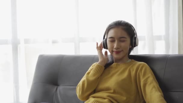 Asyalı Bir Kadının Kulaklık Takıp Evdeki Bir Sopadan Müzik Dinlerken — Stok video