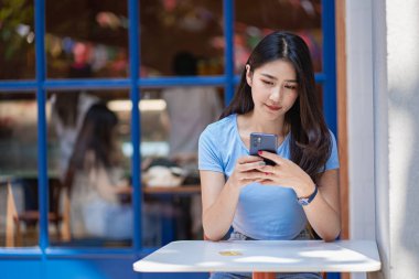 Akıllı telefondan konuşan Asyalı kadın dizüstü bilgisayarda çalışıyor. Başlangıçta güzel bir kız, iş, Asya, kadın, çevrimiçi, KOBİ, tele pazarlama.,