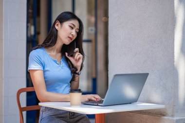 Akıllı telefondan konuşan Asyalı kadın dizüstü bilgisayarda çalışıyor. Başlangıçta güzel bir kız, iş, Asya, kadın, çevrimiçi, KOBİ, tele pazarlama.,