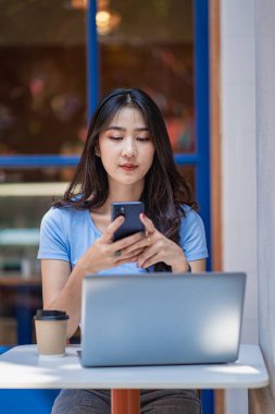 Akıllı telefondan konuşan Asyalı kadın dizüstü bilgisayarda çalışıyor. Başlangıçta güzel bir kız, iş, Asya, kadın, çevrimiçi, KOBİ, tele pazarlama.,