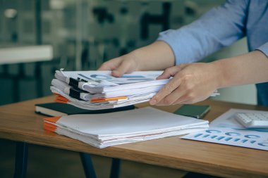 Bir muhasebeci bir yığın dökümanla çalışır. Ofiste mali durum ve performans hesaplaması konseptiyle masaya yatırıldı.