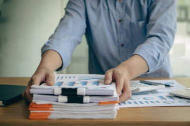 Bir muhasebeci bir yığın dökümanla çalışır. Ofiste mali durum ve performans hesaplaması konseptiyle masaya yatırıldı.